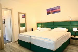 um quarto com uma cama grande e uma cabeceira verde em W2 Ferienwohnung-32609 Hüllhorst em Hüllhorst
