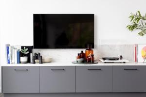a white kitchen with a tv on the wall at Months and Seasons - Momentary Escapes - Coastal House in Wye River
