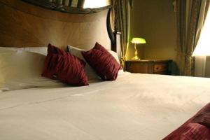 a large white bed with red pillows on it at Denison Boutique Hotel in Rockhampton