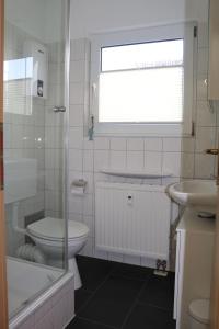 a white bathroom with a toilet and a sink at Ferienwohnung-Moorberg-mit-schoener-Terrasse-in-ruhiger-Lage in Dreschvitz