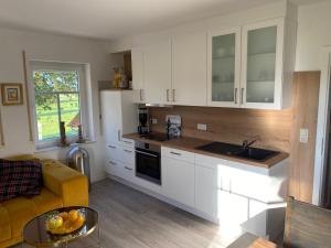 a kitchen with white cabinets and a yellow couch at Ferien-am-Uhlenmeer Keine-Monteure in Apen
