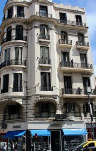 a tall white building with balconies on a street at Hotel Bahia in Buenos Aires