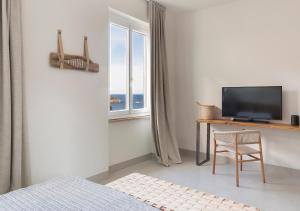 una camera da letto con TV, tavolo e sedia di LA GUARDIA Hotel a Giglio Porto