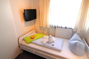 a small room with a bed with towels and a window at Kapitaenshaus-Lassen-Zimmer-Kajuete in Westerland