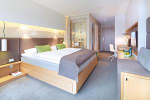 a bedroom with a large bed with green pillows at Strandgut Resort in Sankt Peter-Ording