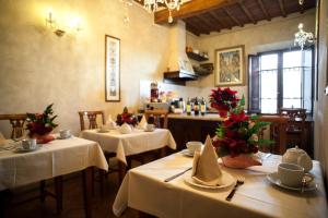 a dining room with tables with white tablecloths and flowers at B&B Palazzo Al Torrione in San Gimignano