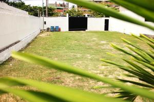 a grassy yard with a white wall and some plants at Hotel Litoral in Aracaju