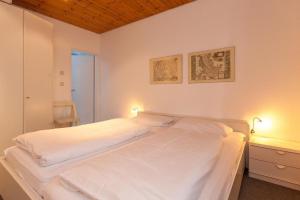 Un dormitorio con una gran cama blanca con dos luces. en Bungalow-Finlandia, en Westerland