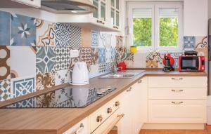 a kitchen with white cabinets and tiles on the wall at Holiday Home Aqua in Šmrika