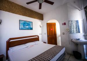 a small bedroom with a bed and a sink at Hotel Candilejas Playa in Veracruz