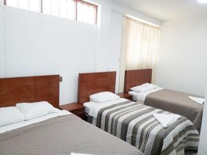 a room with three beds with striped blankets and a window at Shale Hotel in Chachapoyas