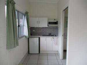 a small kitchen with white cabinets and a microwave at Ingham Tourist Park in Ingham