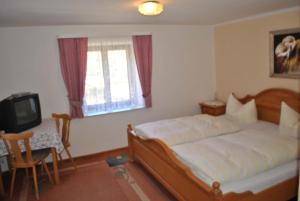 a bedroom with a bed and a table and a television at Zur Alten Dampfsäge - Gasthaus-Pension Weber in Lindberg