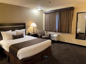 a hotel room with a large bed and a chair at Best Western Plus Pleasanton Inn in Pleasanton +12 photos
