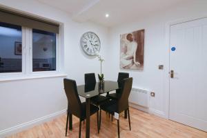 a dining room with a table and chairs and a clock at Long Row Apartments in Nottingham City Centre in Nottingham