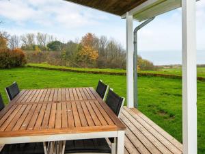 een houten tafel en stoelen op een terras met een veld bij 5 person holiday home in Egernsund in Egernsund