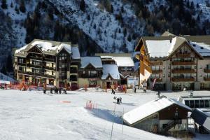 a group of people skiing in the snow in front of buildings at Hotel l'Aigle in Valmeinier