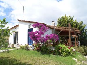 a white house with purple flowers in front of it at Charming Holiday Home in Kritinia with Garden in Kritinía