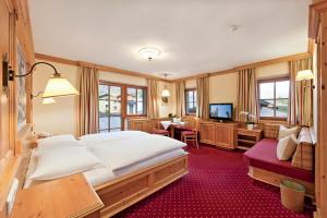 um quarto de hotel com uma cama grande e uma televisão em Eggerwirt Kitzbühel, Hotel & Restaurant em Kitzbühel