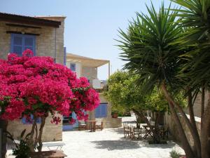 a courtyard with pink flowers and tables and a building at Traditional Village Houses in Skarinou