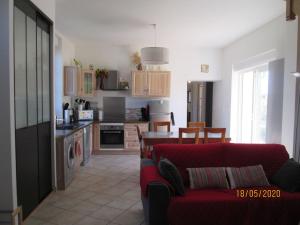 a living room with a red couch and a kitchen at Comfy holiday home in Crux La Ville with fenced garden in Crux-la-Ville