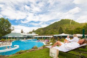 a group of people sitting on a bench next to a pool at Hotel Tannenhof in Bad Harzburg