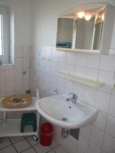 a white bathroom with a sink and a mirror at Apartment-3 in Schönhagen
