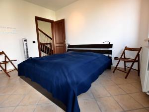 a bedroom with a bed with a blue blanket on it at Belvilla by OYO La Torre in Belvedere Langhe