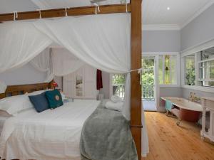a bedroom with a canopy bed and a bath tub at Lilly Pilly Arthouse in Stanwell Park
