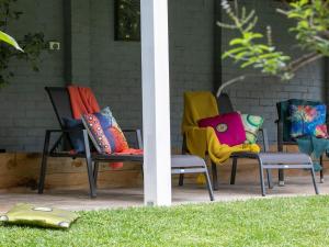 two chairs with colorful pillows sitting on a porch at Lilly Pilly Arthouse in Stanwell Park