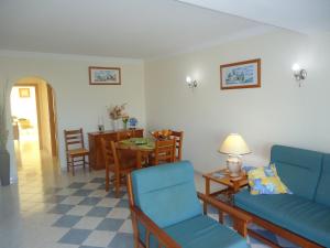 een woonkamer met een bank en een tafel en stoelen bij Vilas do Mar in Carvoeiro