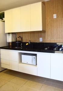 a kitchen with white cabinets and a microwave at Ana marinho flat 702 in Natal
