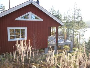 a red house with a deck in the woods at Chalet in Torsby Municipality Middle with Sauna in Gunsjögården
