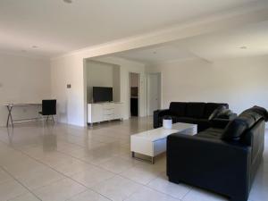 sala de estar con 2 sofás negros y TV en Townsville Wistaria Spacious Home en Townsville