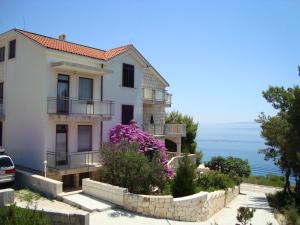 a white house with purple flowers in front of the ocean at Villa Adagio Apartments in Sumartin