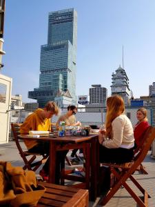 un grupo de personas sentadas en una mesa en una azotea en Peace House Suzunami, en Osaka