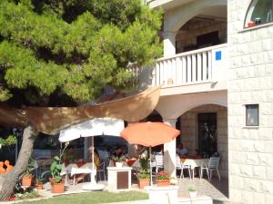 a patio with tables and chairs and an umbrella at Villa Adagio Apartments in Sumartin