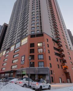 un edificio alto con coches estacionados frente a él en Elite apartments en Astaná