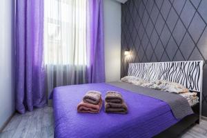 una camera da letto con lenzuola viola e asciugamani su un letto di 8 Svyatoho Teodora Square Apartments a Lviv