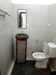 y baño con lavabo, aseo y espejo. en RIKNA BEACH HOUSE, en Watukarung