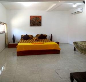 1 dormitorio con 1 cama amarilla en una habitación en RIKNA BEACH HOUSE, en Watukarung