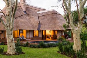 une maison avec un toit de chaume et une piscine dans l'établissement ANEW Hotel Hluhluwe, à Hluhluwe