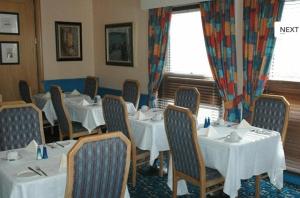 une salle à manger avec des tables et des chaises blanches dans l'établissement Preston Park Hotel, à Brighton et Hove