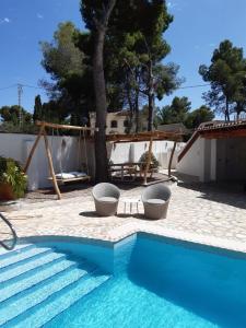 einen Pool mit zwei Stühlen neben einem Haus in der Unterkunft Casa Verano eterno, Villa tot 16 personen in Benissa