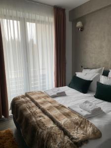 a large bed in a room with a large window at Edelweiss Apartments SILVER RESORT POIANA BRASOV in Poiana Brasov