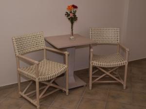 2 chaises et une table avec un vase de fleurs dans l'établissement Hotel Theasi, à Diakopto
