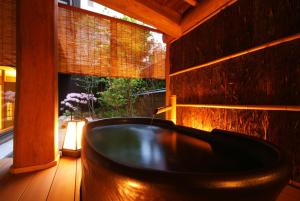 a bath tub in a room with a window at Kinosaki Onsen Nishimuraya Hotel Shogetsutei in Toyooka