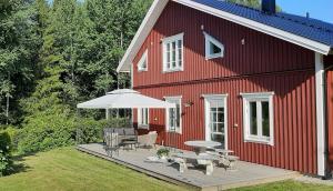 a red house with a deck with chairs and an umbrella at B&B Friendsroom 2 persons in Mellerud