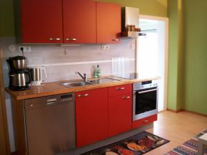 - une cuisine avec des placards rouges et un évier dans l'établissement Das Steghaus, à Gräfenberg