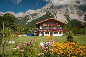 a house with flowers in front of a mountain at Landhaus Katharina in Ramsau am Dachstein +9 photos